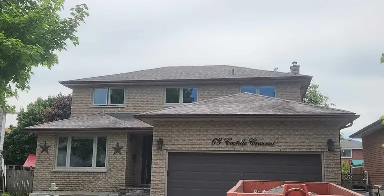 A roofer repairing shingles on a residential roof