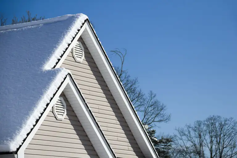A snow-covered roof being cleared in winter